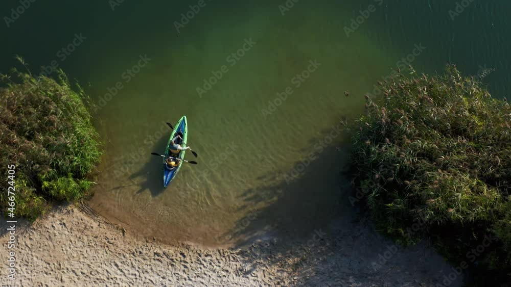 Aerial drone of young family kayaking together on peaceful lake. Father and son training to sail kayak inflatable boat across the river. Top flight view. Aerial drone of young family kayaking together on peaceful lake. Father and son training to sail kayak inflatable boat across the river. Top flight view.