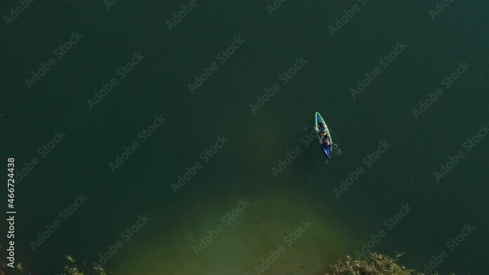 Aerial topdown shot father and son wearing swimsuits kayaking together on peaceful deep blue sea water. Kayaking activity. Families. Aerial topdown shot father and son wearing swimsuits kayaking together on peaceful deep blue sea water. Kayaking activity. Families.