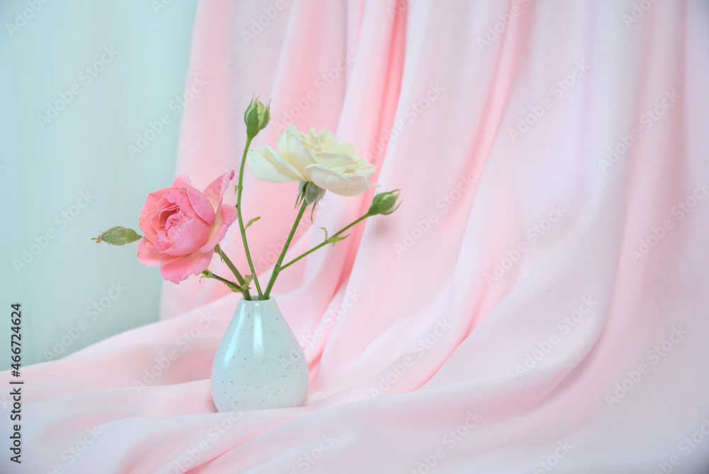Obraz premium Pink curtain, bright red and white roses in a white vase, copy space
