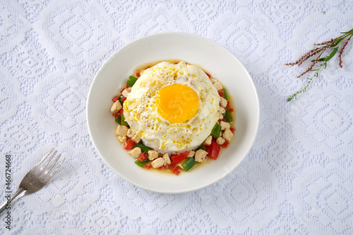 Top view of rice bowl with egg, chicken, green and red peppers; a fork