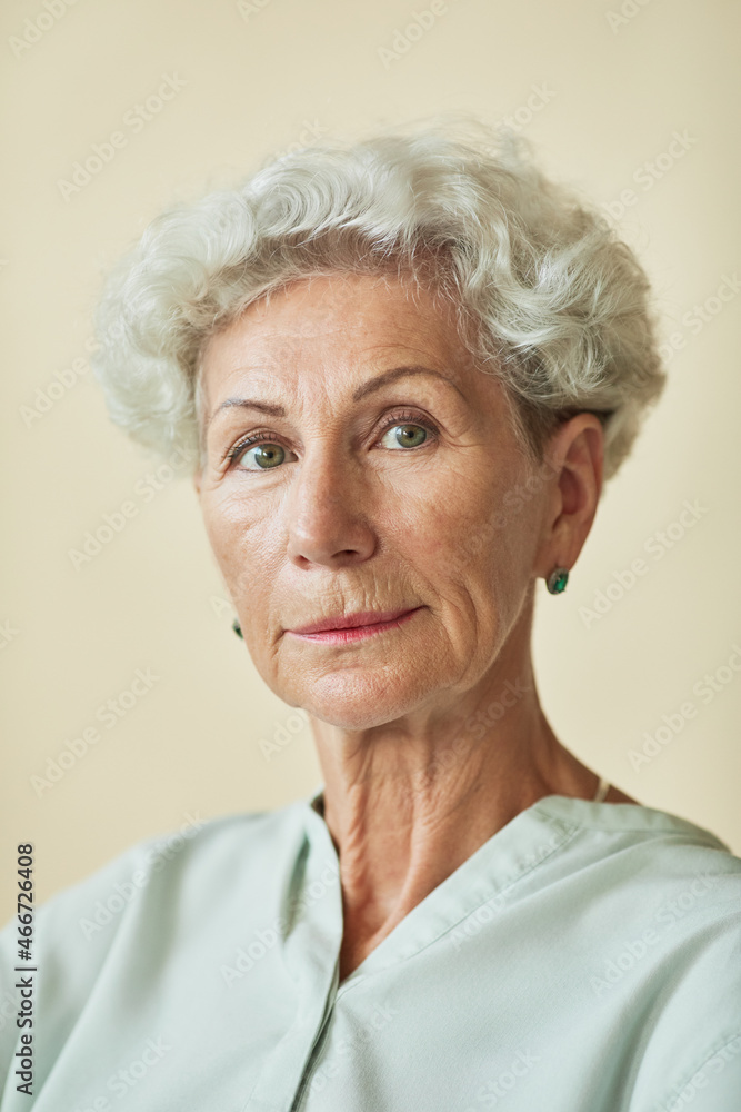 Vertical portrait of elegant senior woman looking at camera against neutral background Vertical portrait of elegant senior woman looking at camera against neutral background