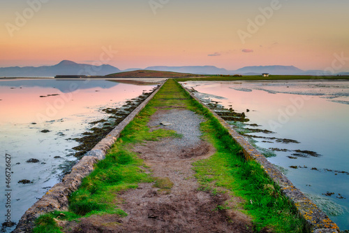 A pastel sunset over a dike with a view of the mountains. Mayo County  Ireland