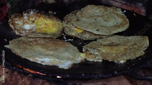 Frying Newari bara with eggs and meat on a skillet over a fire. photo