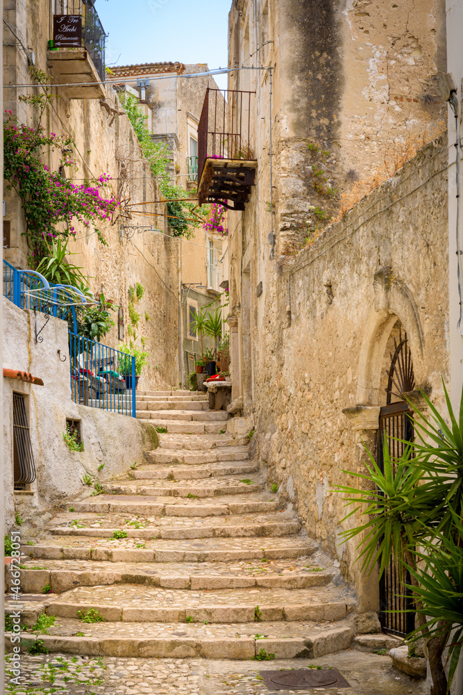 Typical Italian medieval street in Peschici village, Puglia, Southern Italy, with a stone staircase, traditional stone house and balconies, a summer holiday destination