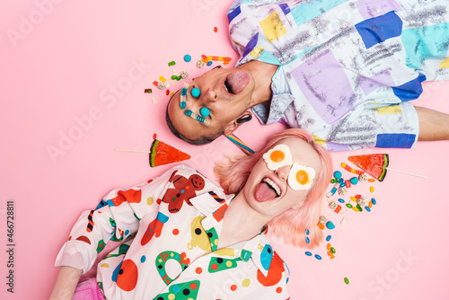 Young couple making fun with candies while lying on floor