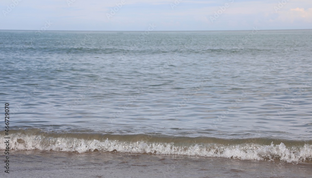 simple background of calm sea with low waves on the sandy shore of the beach