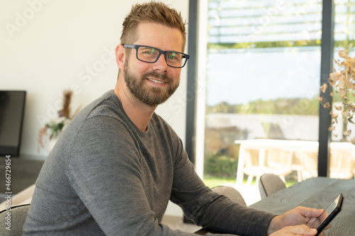 Close up portrait of young smiling man using tablet in the living room