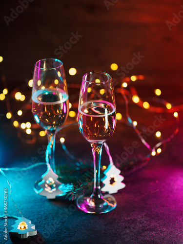 Two glasses of sparkling wine, neon background and bokeh garlands.