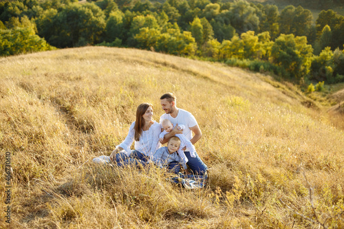 a family with small children on a background of tall grass lies on a calety blanket