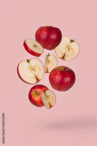 Fresh sliced and whole apple floating in the air isolated on pastel pink background.