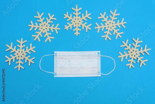 Medical mask on a blue background with snowflakes. Top view with copy space, space for text. Celebrating the New Year. Happy New Year 2022 concept