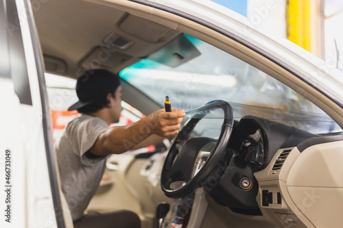 Male specialist applying window tinting film on the car.