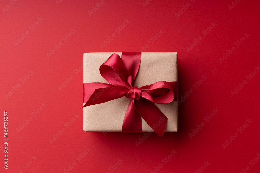 Top view on Christmas gift box with red bow on red background. Top view on Christmas gift box with red bow on red background.