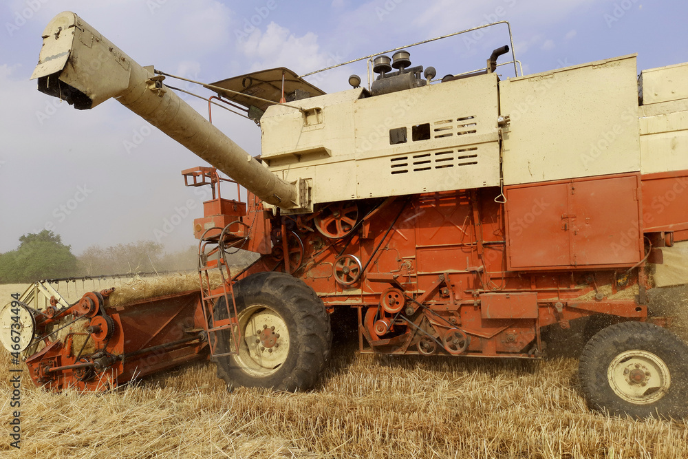 Combines harvester harvesting wheat on a bright day. Wheat cutting machine. Wheat harvesting by the combine Combines harvester harvesting wheat on a bright day. Wheat cutting machine. Wheat harvesting by the combine