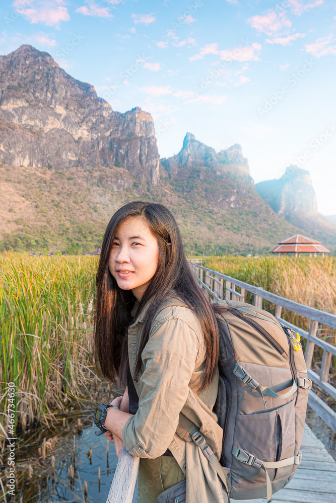 Freedom traveler woman standing with raised arms and enjoying a beautiful nature and cheering young woman backpacker at sunrise seaside mountain peak