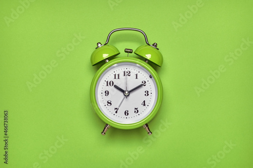 Green alarm clock on light green background