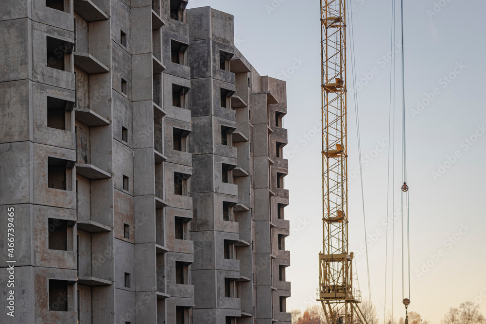 Construction of a high-rise residential building evening. Lighting by the setting sun. Tower crane during the construction of a reinforced concrete house. Construction of a high-rise residential building evening. Lighting by the setting sun. Tower crane during the construction of a reinforced concrete house.