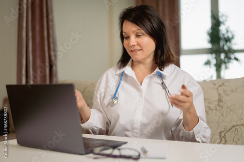 Female general practitioner wears white coat speaking videoconferencing on laptop computer using online video call consultation app. telemedicine.. female doctor consults patient