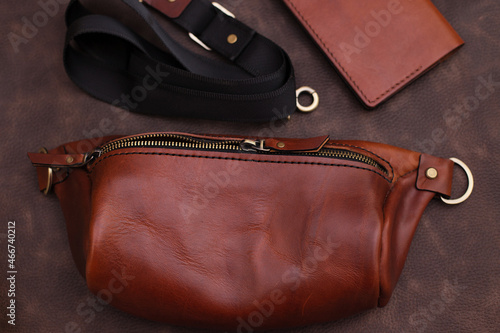 open women's brown leather bag on a brown background, top view. Products made of genuine soft leather. Waist bag, shoulder bag. Zipper bag