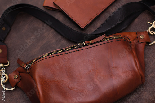 open women's brown leather bag on a brown background, top view. Products made of genuine soft leather. Waist bag, shoulder bag. Zipper bag