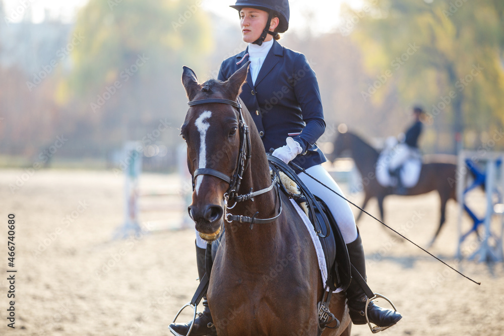 Young teenage girl riding horse before her show jumping test in equestrian competition