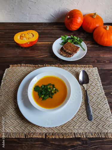 Top view of pumpkin soup with parsley and green onions on dark wooden table