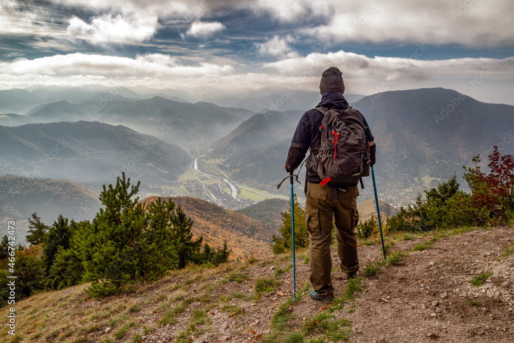 Hiker with trekking poles looking from top of the hill Sip in Slovakia
