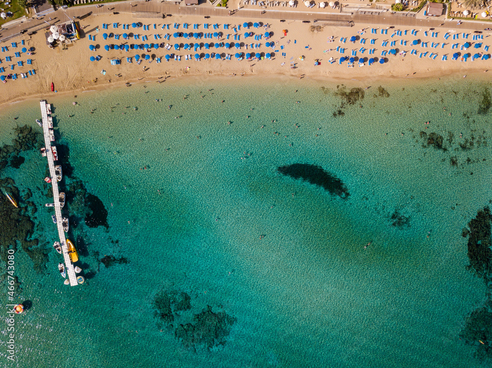 Aerial view of sun loungers on beach with clear sea