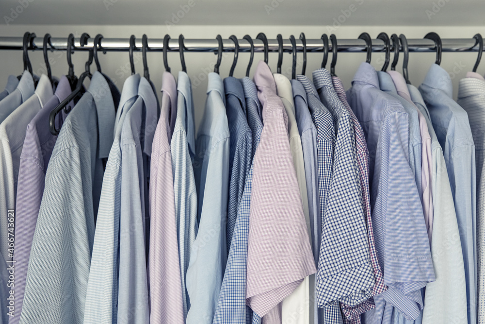 Mens shirts on hangers in the closet. Blue and pink shades. Storage of clothes.