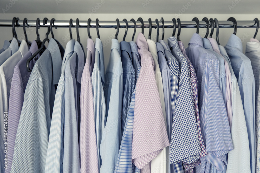 Mens shirts on hangers in the closet. Blue and pink shades. Storage of clothes. Mens shirts on hangers in the closet. Blue and pink shades. Storage of clothes.
