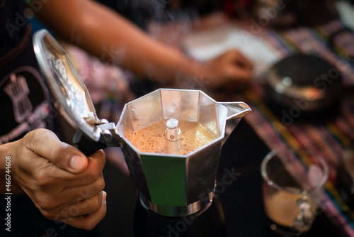 hand holding a pot of boiling coffee. hot coffee in a pot.