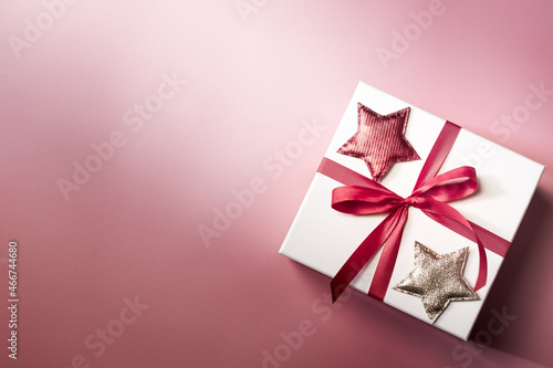 White gift box with red ribbon on pink background, christmas day present. A box for surprise in holiday. © Boykowit