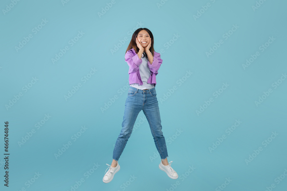 Shocking sale. Surprised amazed young asian lady jumping in air and touching face with amazement, blue background Shocking sale. Surprised amazed young asian lady jumping in air and touching face with amazement, blue background