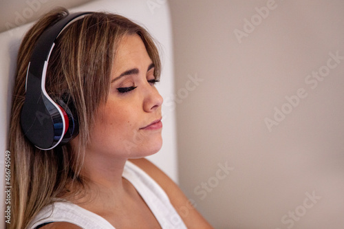 Photos Mujer escuchando música con auriculares sentada en la cama de su habitación