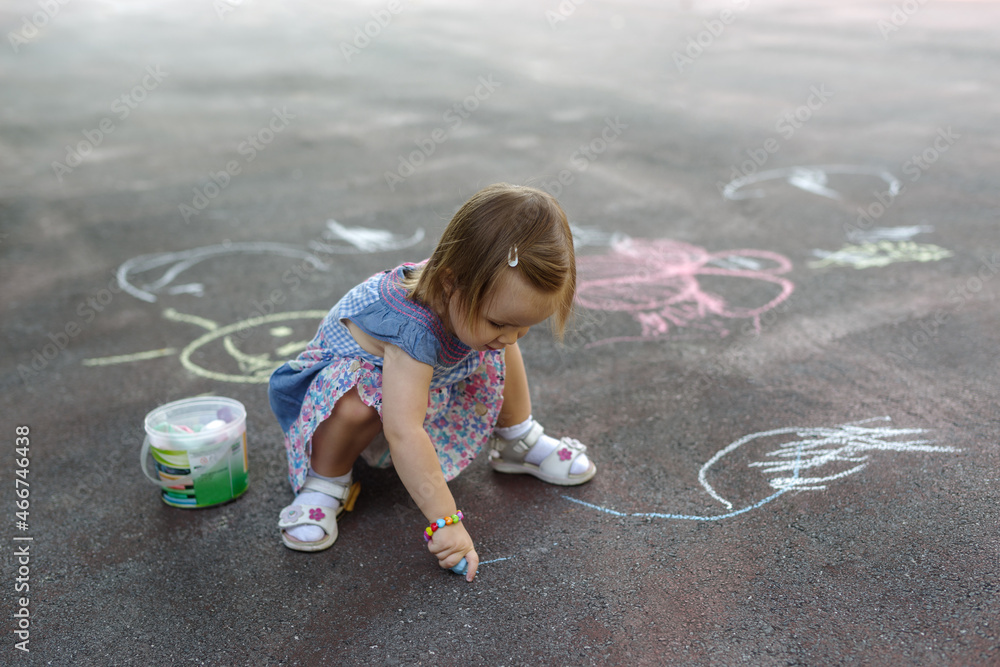Naklejka premium Overhead shot of a little girl scribbling in colourful chalk on pavement