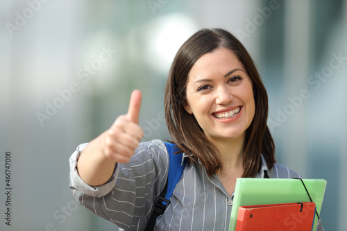 Happy student gestures thumbs up lloking at you photo