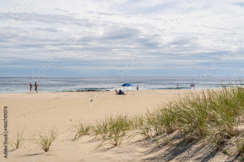 Scenic beach scene with joggers and people under beach umbrella at the Jersey  shore