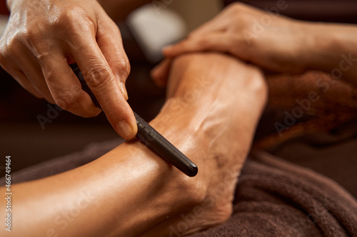 Practitioner using reflexology stick during Thai foot massage session photo