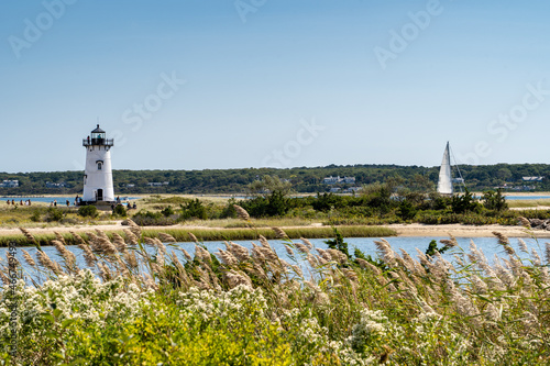 Edgartown Harbor Light lighthouse with wild grass and sailboat on Martha's Vineyard, Massachusetts