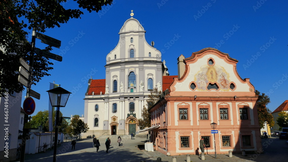 altes Franziskanerhaus und schöne Basilika St. Anna mit Menschen im Wallfahrtsort Altötting bei blauem Himmel