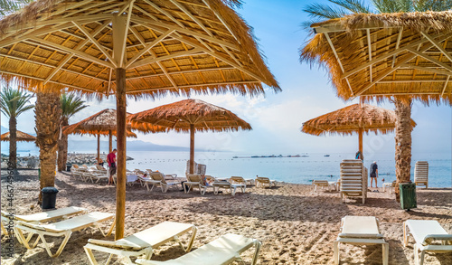 Fototapeta Naklejka Na Ścianę i Meble -  Morning at sandy beach of the Red Sea, panoramic view from central stone walking pier and promenade in Eilat - famous tourist resort city in Israel