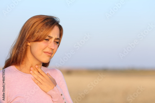 Woman suffering sore throat in a field