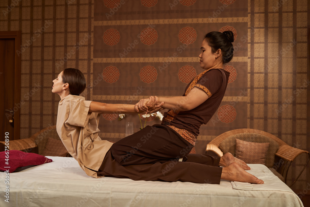 Φωτογραφία Practitioner stretching her client back muscles during Thai massage session