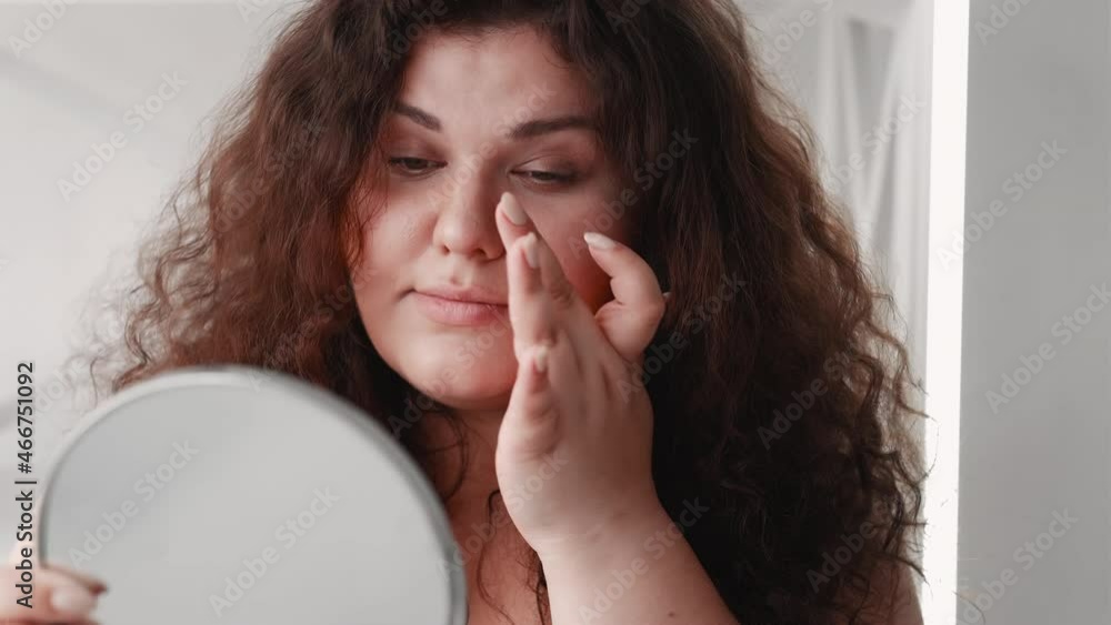 Beauty care. Healthy hair. Body positive. Happy pretty overweight obese woman admiring curly styling smooth flawless face skin at mirror reflection at home. Beauty care. Healthy hair. Body positive. Happy pretty overweight obese woman admiring curly styling smooth flawless face skin at mirror reflection at home.