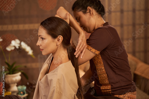 Pensive young client receiving Thai stretching massage