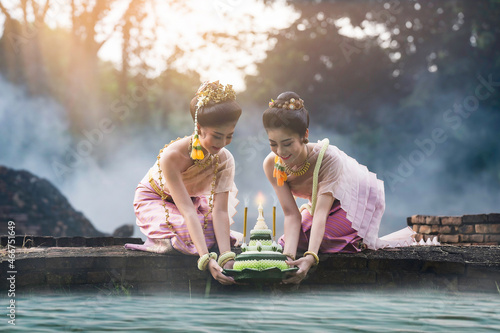 Loy krathong tradition , Beautiful women dressed in Thai national costumes. Put the Krathong on the river, The word krathong refers to basket and loy means to float photo