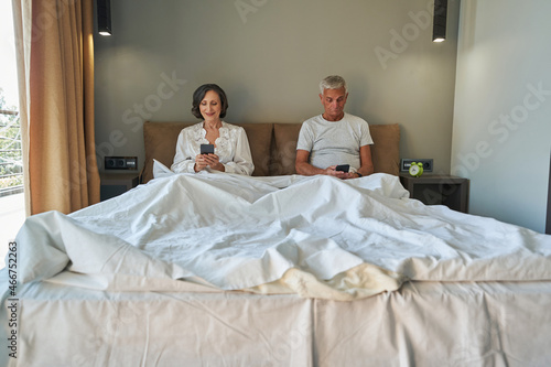Elderly people surfing internet on smartphones from bed