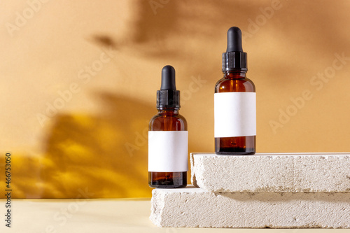 Face and body skin care products in a glass bottle with a pipette on a concrete podium. Cosmetics for women with natural ingredients. Copy space, layout