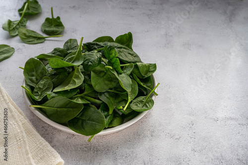 Fresh spinach leaves in a bowl on gray background. Healthy food ingredient