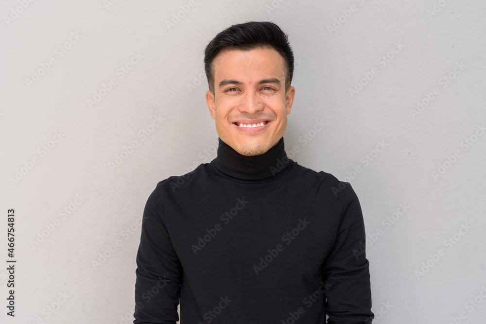 Portrait of handsome young man smiling against gray background Portrait of handsome young man smiling against gray background